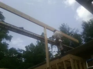 Carpenter setting a ridge beam over a new addition frame — Ice Dam Removal by Roofing Brothers in Ashburnham