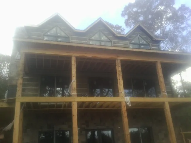 Dormers and porch framing on a large log home under construction — Roof Coating work by our crew in Ashburnham