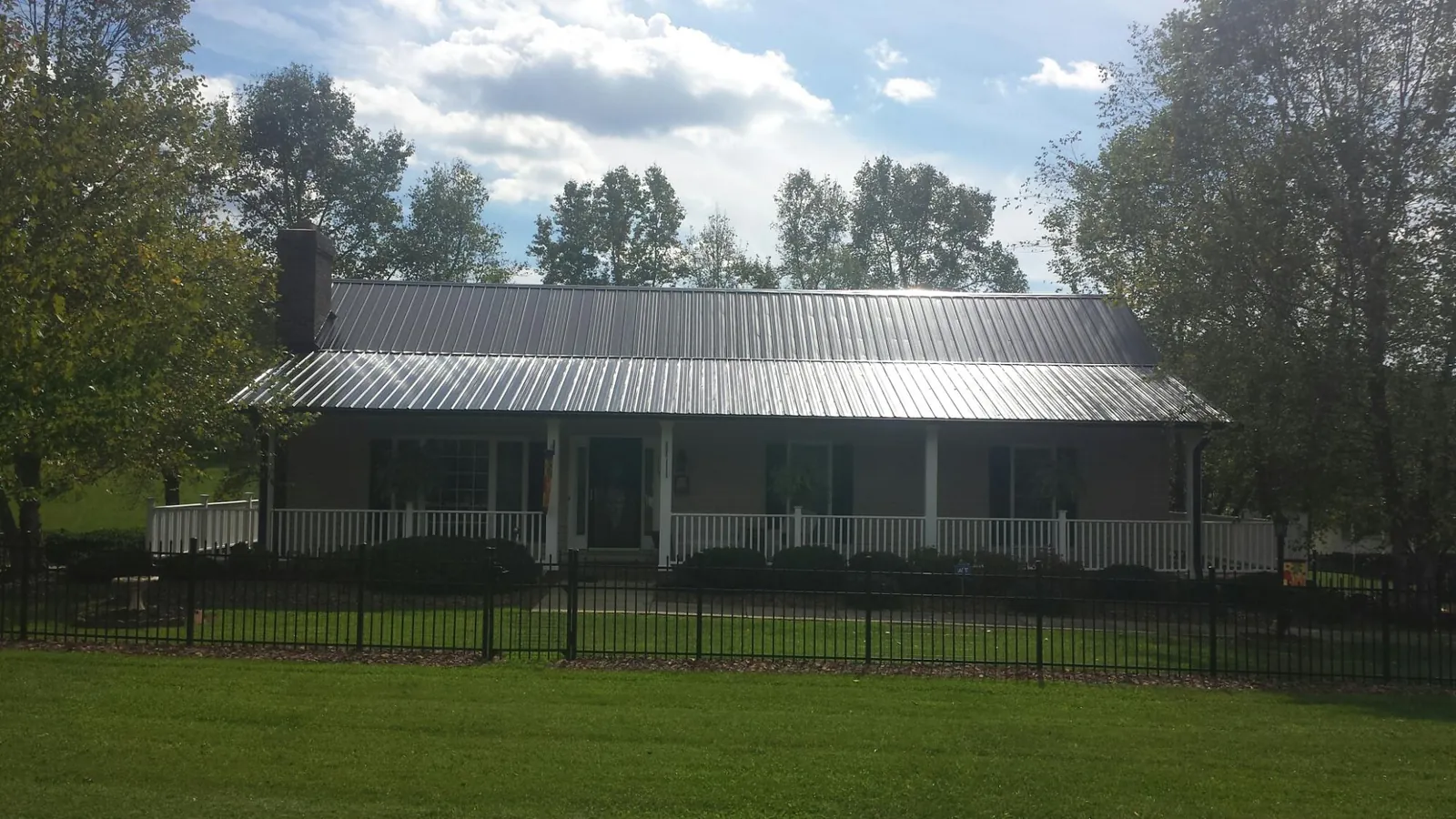 Gray metal roof on a brick ranch with a full width front porch — Gutter Guard Installation work by our crew in Ashburnham