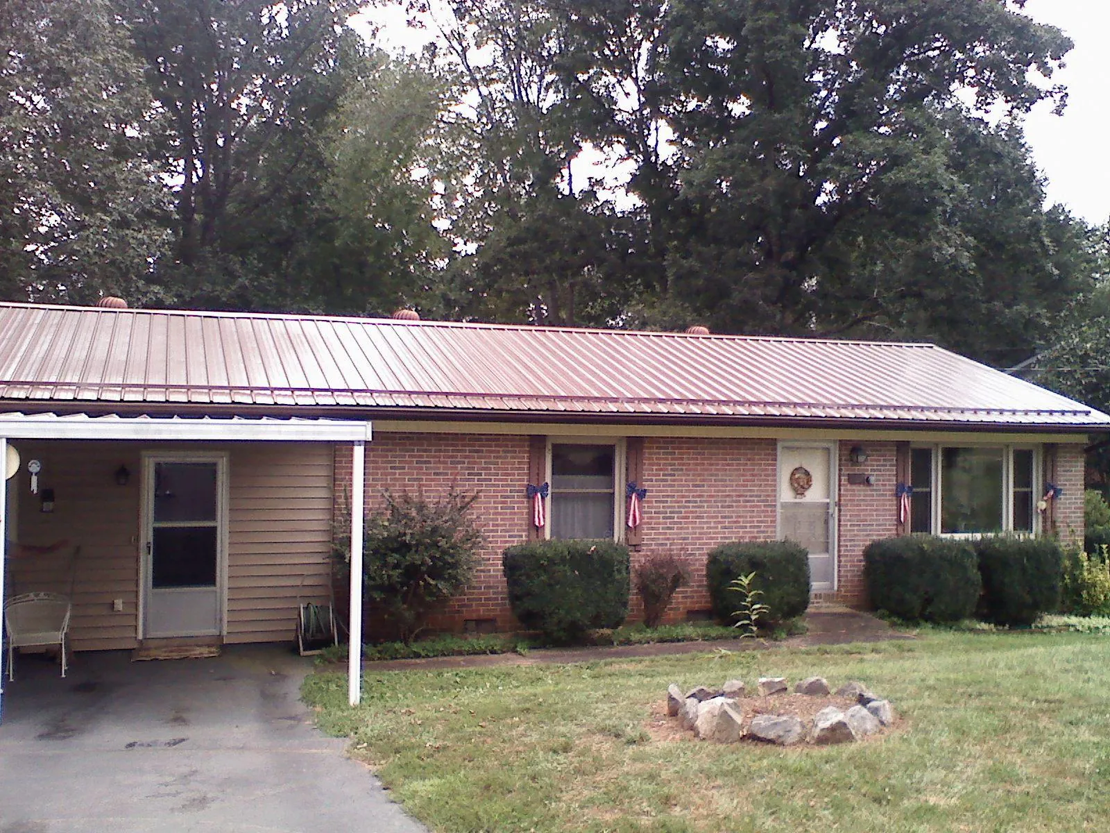 Bronze metal roof and carport on a brick ranch home — Roof Repair work by our crew in Ashburnham