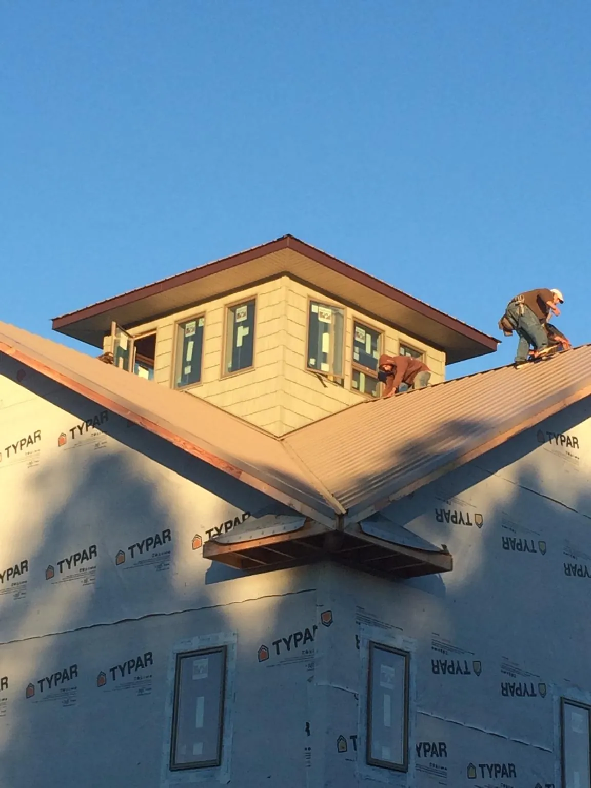 Roofers working around a rooftop cupola on a new metal roof at sunset — Roof Waterproofing in Ashburnham by Roofing Brothers
